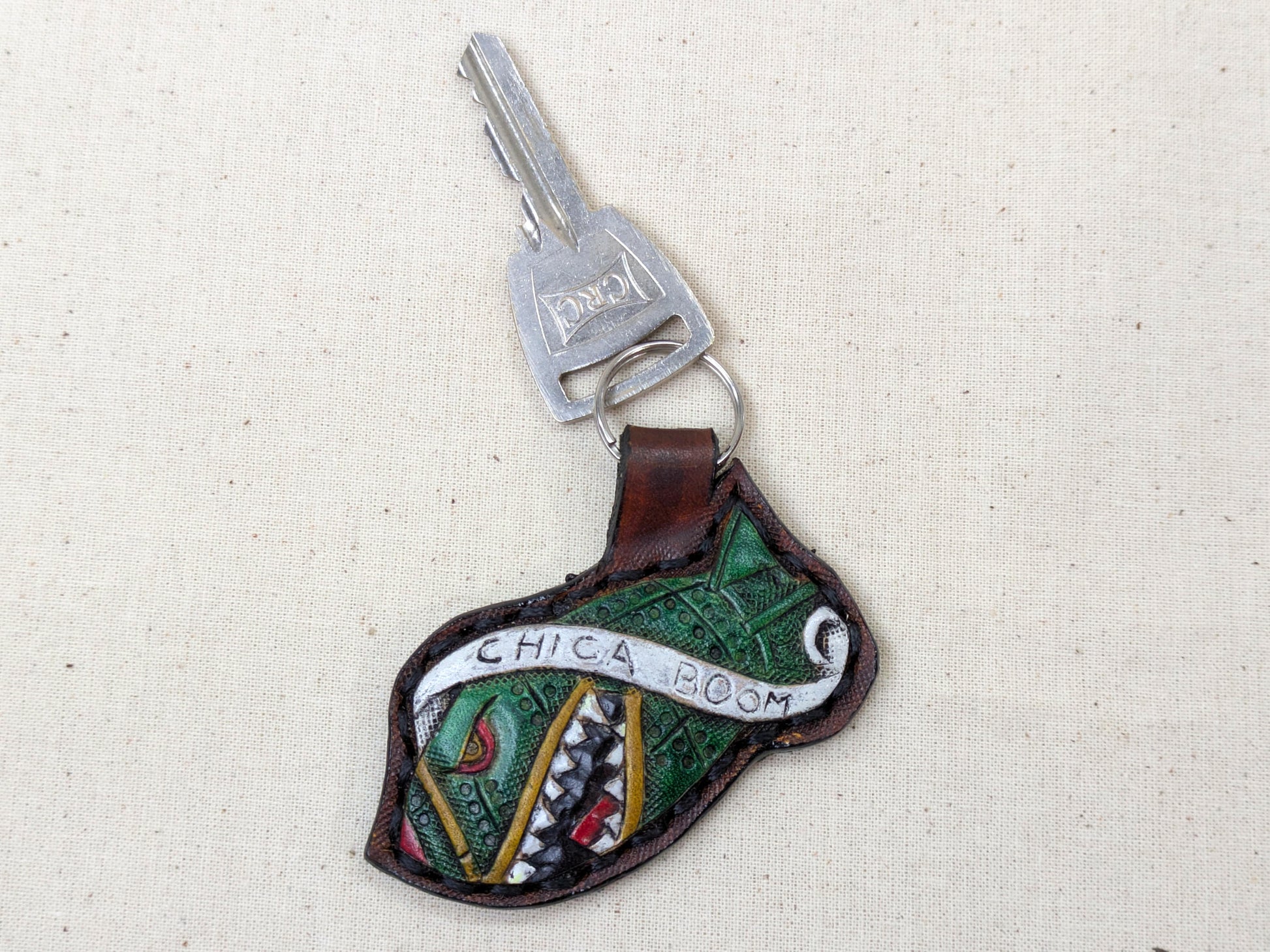 Keychain with decorative design and 'Chica Boom' text on a textured beige background