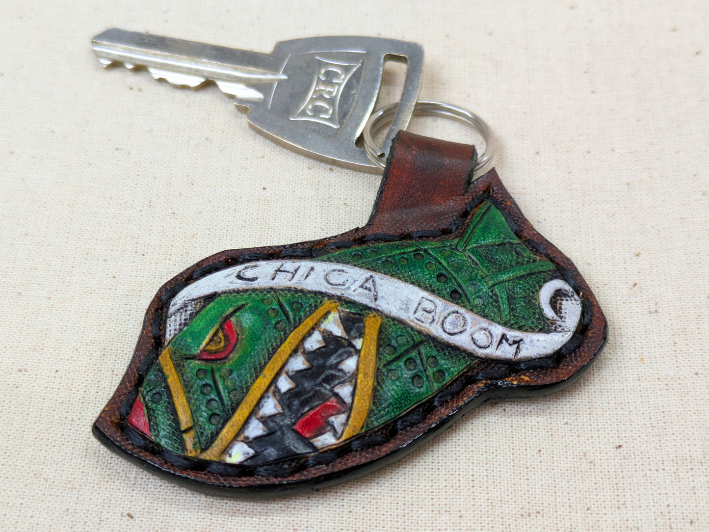 Keychain with colorful design and 'Chica Boom' text on a beige background