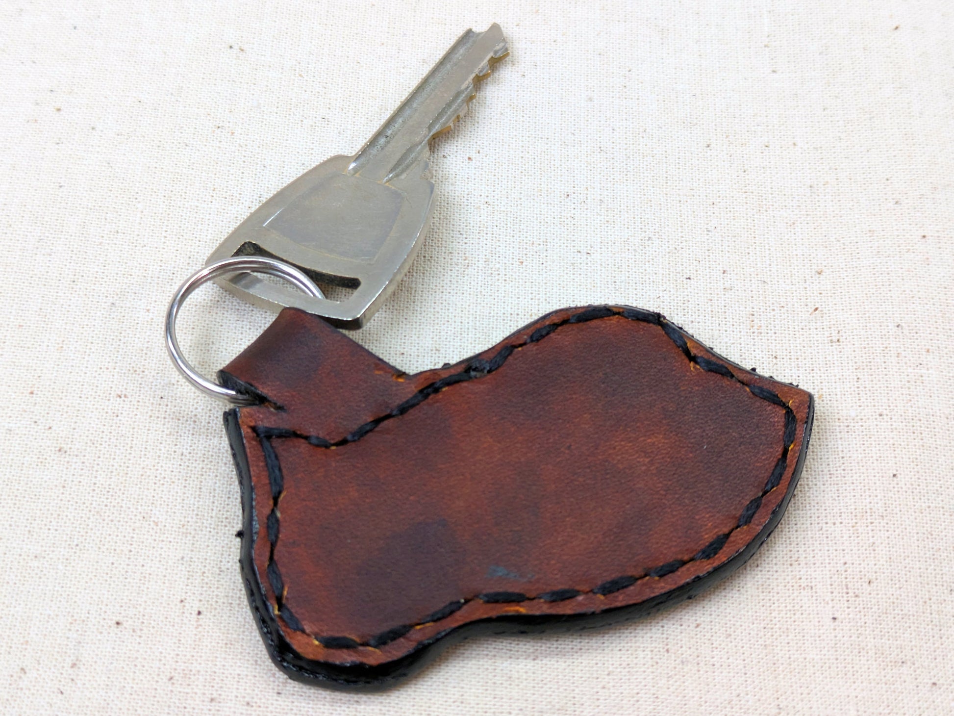 Brown leather keychain with keys on a light gray background
