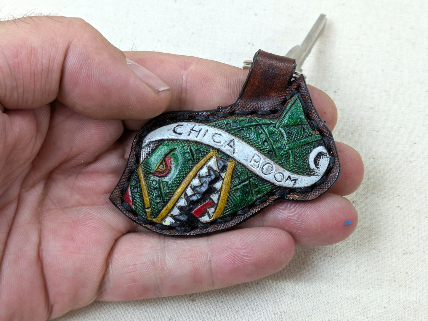 Colorful leather patch with 'Chica Boom' text held in a hand against a white background