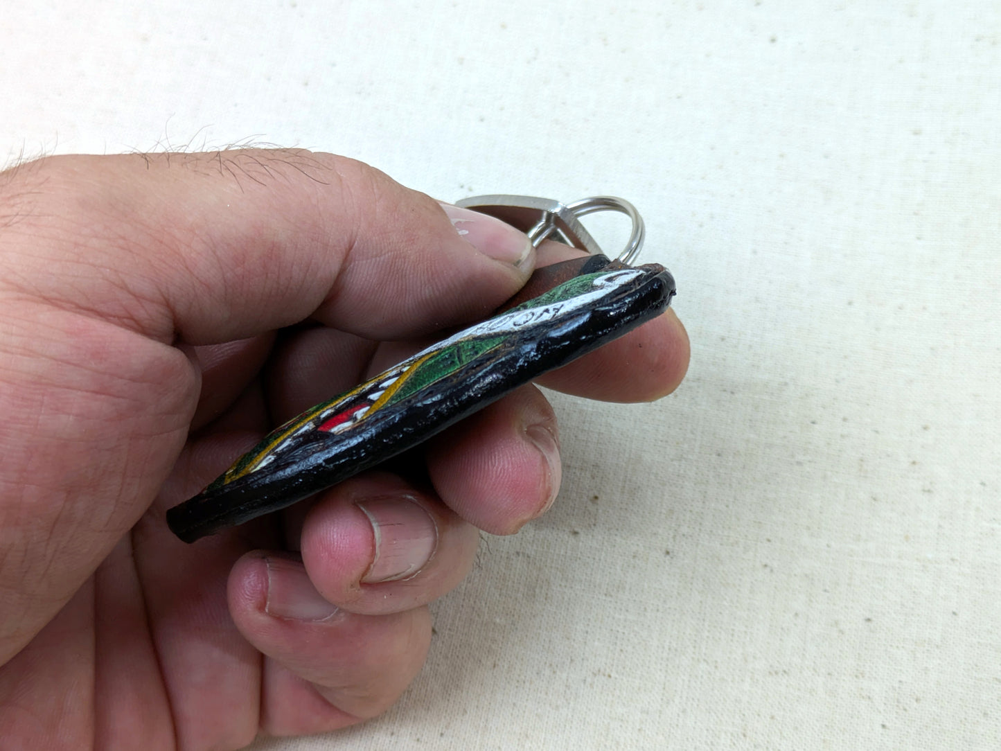 Hand holding a keychain with a colorful design on a white background